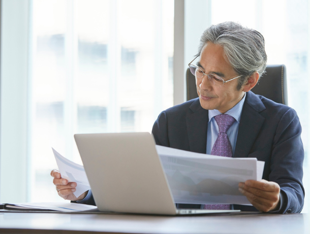 A senior lawyer reviewing documents in front of a laptop, symbolizing the importance of legal due diligence in AI product launches.