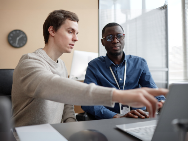 Two professionals discussing something on a laptop screen, symbolizing collaboration between legal and technical teams in AI product development.