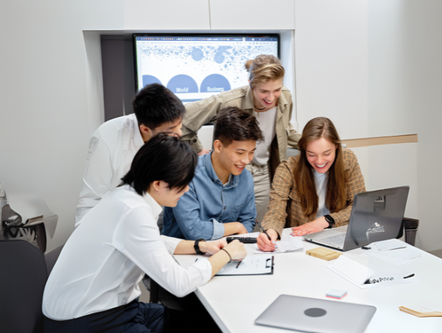 A group of young professionals collaborating around a laptop and documents, symbolizing teamwork in reviewing AI vendor agreements and legal clauses.