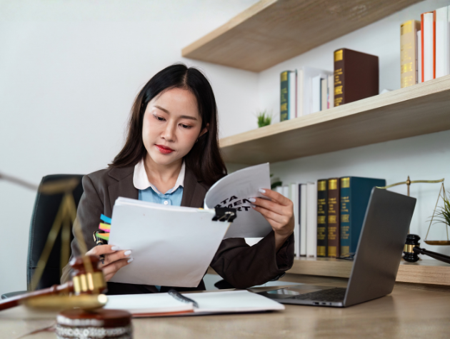A lawyer reviewing documents at a desk with a laptop, symbolizing the decision-making process behind creating a risk menu for legal interventions.